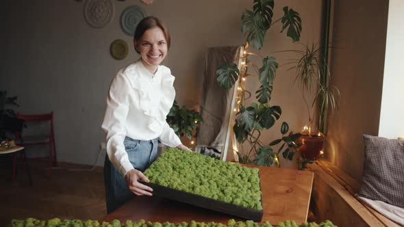Smiling Young Girl Holding a Large Picture of Decorative Stabilized Moss in Her Hands