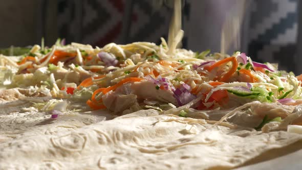 Close-up on the table in the kitchen preparing shawarma sprinkling cheese on the filling. Delicious 