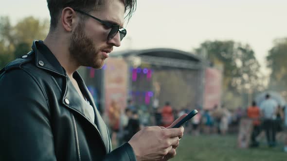 Young caucasian man on music festival using phone. Shot with RED helium camera in 8K.