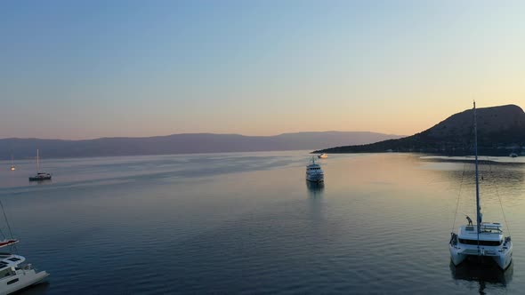 Catamaran and Sail Yachts Anchored at Bay on Deep Blue Sea Water on Sunrise