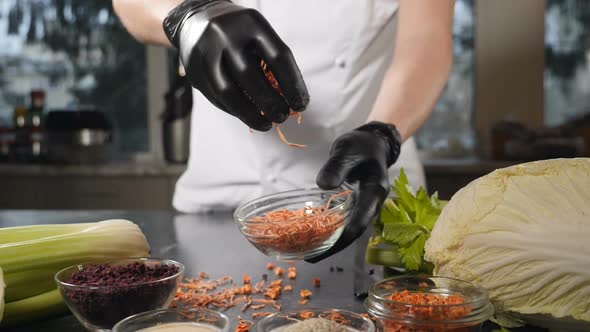 Chef in Black Gloves Sprinkling a Handful of Dried Sliced Carrots