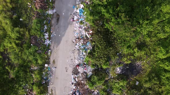 Aerial fly over rural path with rubbish dump