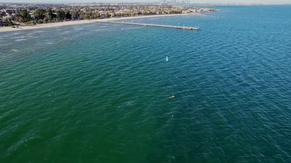 Drone following Kite surfer with a pier in the back ground.