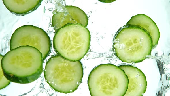 Super Slow Motion Shot of Cucumber Slices Falling Into Water on White Background at 1000Fps.