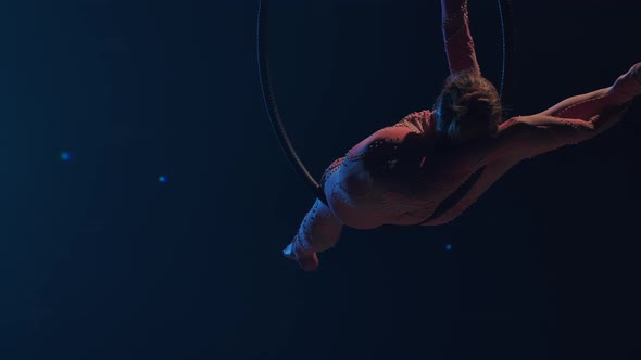 A Young Woman Gymnast Performs Acrobatic Stunts on an Air Hoop Under the Dome of a Circus and