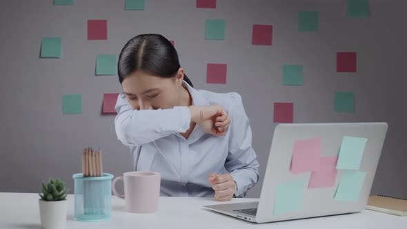 Asian woman working at home office was sick with sore throat and cough in her elbow.