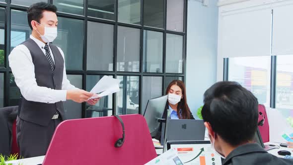 Asian young businessman and woman working on laptop computer in office with new normal lifestyle.