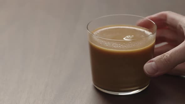 Slow Motion Man Hand Takes Coffee with Cream From Walnut Wood Table with Copy Space