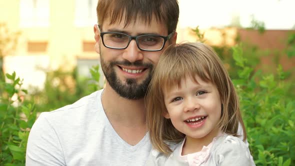 Father with Girl Sit in Summer Park Look at Camera Smile and Laugh