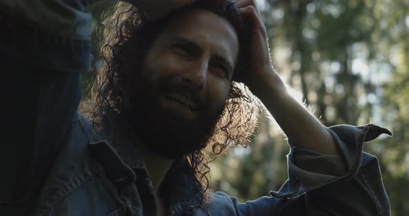 a Happy Man in a Denim Jacket Laughs and Ties His Hair Freely Talking in the Background of the Sun