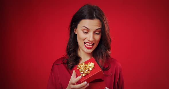 Beautiful Woman Enjoys a Valentine's Gift on a Red Background