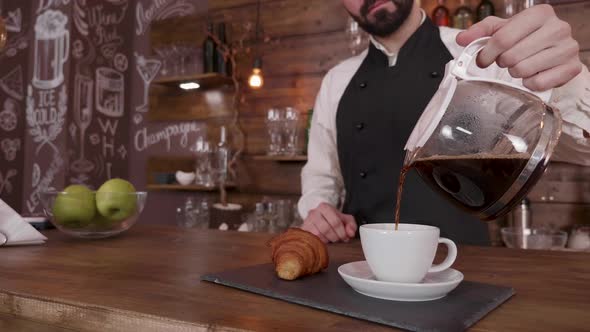 Barista Man While He Holds a Pitcher and Pour Coffee in a Empty Cup