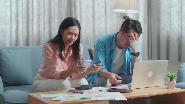 Couple With A Laptop Holding Credit Card And Smartphone Having Headache Due To Unable Pay Money