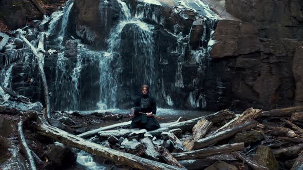 Man Practicing Kendo with Bamboo Sword on Waterfall Background