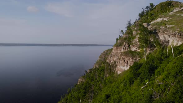 Flight Along a Picturesque Cliff Above the River. A Huge Reservoir and a Steep Stone Cliff.