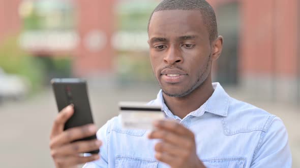 Outdoor Portrait of African Man Making Online Payment on Smartphone
