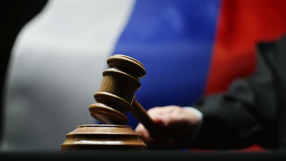 Judge With Gavel In His Hand Hammering Against Waving Russian Flag Courtroom