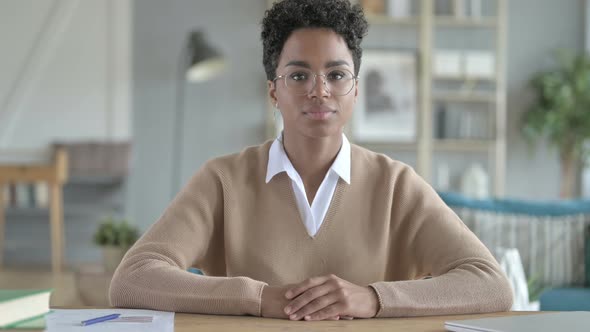 Young African Girl Smiling And Sitting At Her Working Table