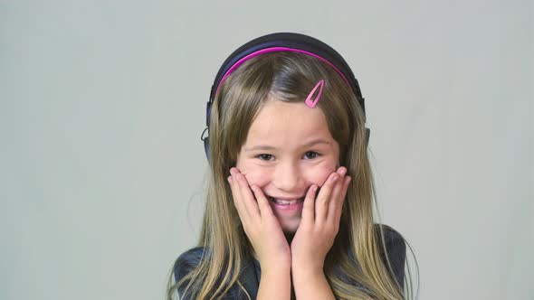 Pretty Smiling Cild Girl Listening to Music in Big Pink Earphones