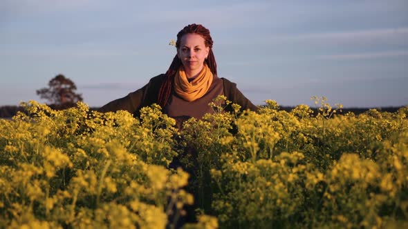 a red-haired girl in a field of various flowers looking into the distance