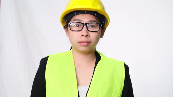 Woman technician smiling with helmet and showing a heart shape with hands on white background.