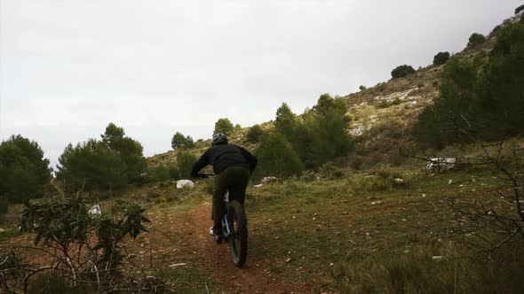 Cyclist riding bike on rocky path in forest
