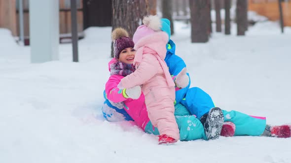 Delighted Mom and Dad Hug Little Daughter Lying on Snow