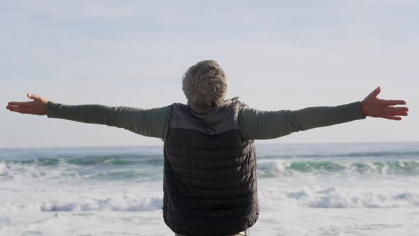 Caucasian woman enjoying free time by sea on sunny day standing with arms wide