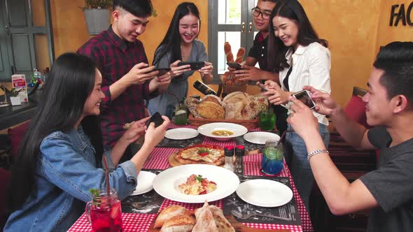 Group Of Friend Take A Picture With Mobile Phone Before Have Lunch In Restaurant