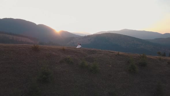 Newlyweds Running on a High Slope of the Mountain. Groom and Bride. Aerial View