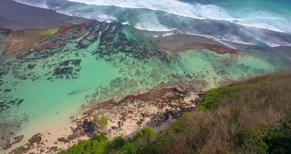 Aerial drone view of a coral reef and waves at the beach.