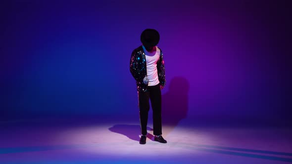 Young Stylish Man Dancing in Style Michael Jackson, Spotlight on a Blue Background.