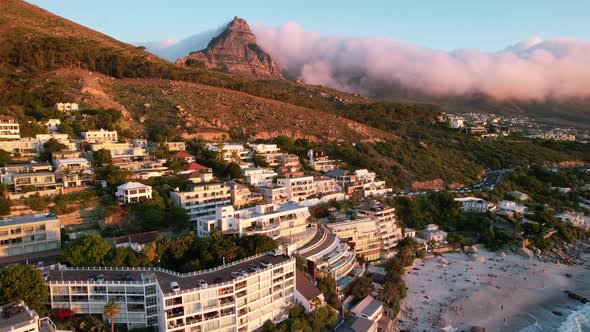 sunset of hotels at Clifton Beach with clouds rolling over lions head in Cape Town, aerial