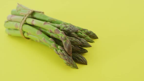 Video of close up of bundle of fresh asparagus over green background