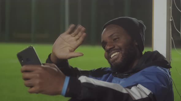 Man Video Calling on Soccer Pitch