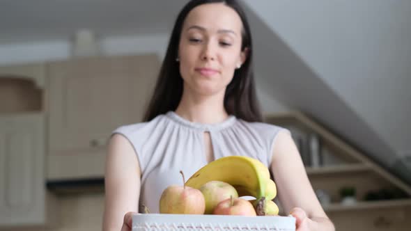 Young Woman Holding Fruits in Her Hands Apples and Bananas She Smiles and Looks at the Camera