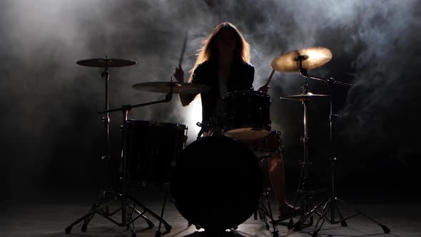 Girl Is Kicks From Playing Drums, Playing Energetic Music. Black Smoke Background. Silhouette