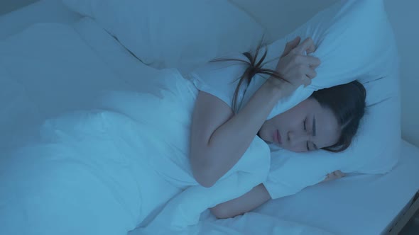Attractive young woman lying down with upset and angry feeling due to noise and put cozy blanket.