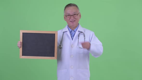 Happy Mature Japanese Man Doctor Holding Blackboard and Giving Thumbs Up