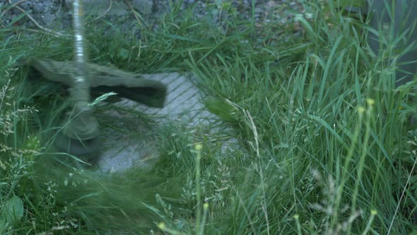 Man mows green grass. Man mowing grass with gasoline braid. Farmstead overgrown with grass.