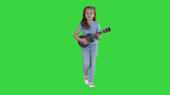 Little Girl Singing and Playing Small Guitar While Walking Towards Camera on a Green Screen, Chroma