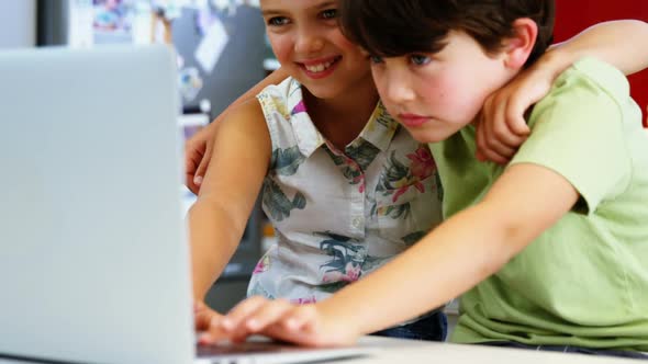 Siblings using laptop in kitchen