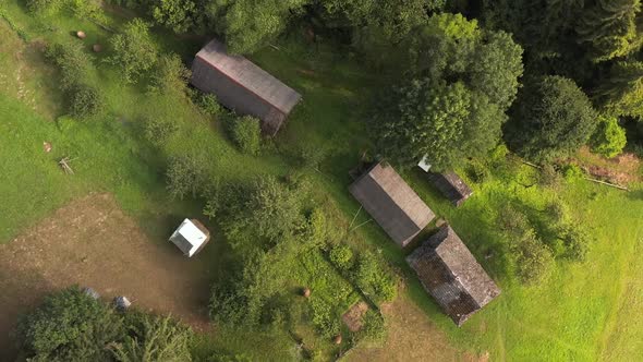 Aerial drone view of the yard with an old wooden hut on mountain slope