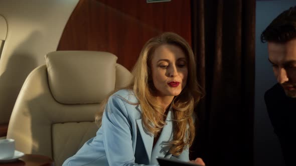 Businesswoman Show Tablet Computer to Gentleman in Luxury Business Jet Closeup