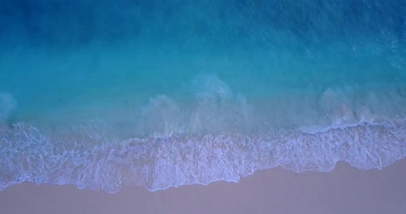 Beautiful overhead clean view of a white sand paradise beach and aqua blue water background in color