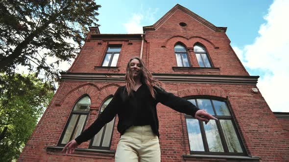 A Young Girl is Actively Posing Against the Backdrop of a Brick Building