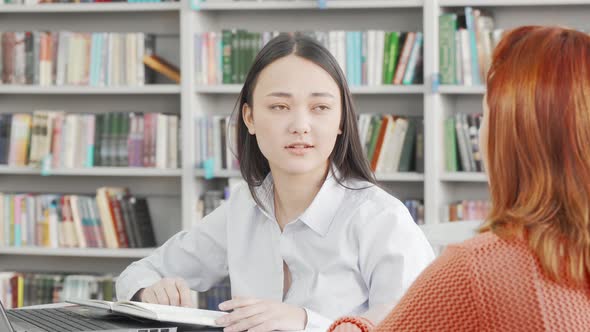 Asian Young Woman Talking To Her Friend at College Library