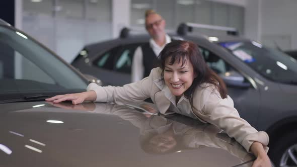 Portrait of Excited Fascinated Beautiful Woman Touching Brand New Luxurious Car with Loving Man