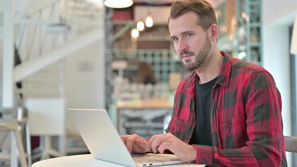 Thumbs Down By Disappointed Young Man with Laptop in Cafe 