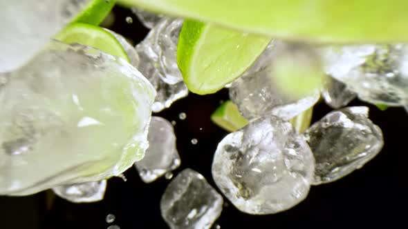 Super Slow Motion Shot of Lime Slices and Ice Cubes Falling on Black Background at 1000 Fps